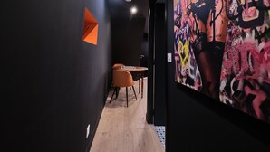 Un corridoio con pavimento in legno, un tavolo con sedie e un grande quadro astratto appeso al muro.