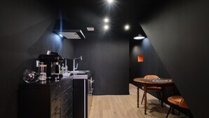 Una cucina moderna con una macchina per il caffè, un tavolo da pranzo con sedie e un pavimento in legno.