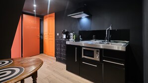 Una cucina moderna con forno integrato, microonde e lavello. Si vede un tavolo in legno e un armadietto con cassetti.