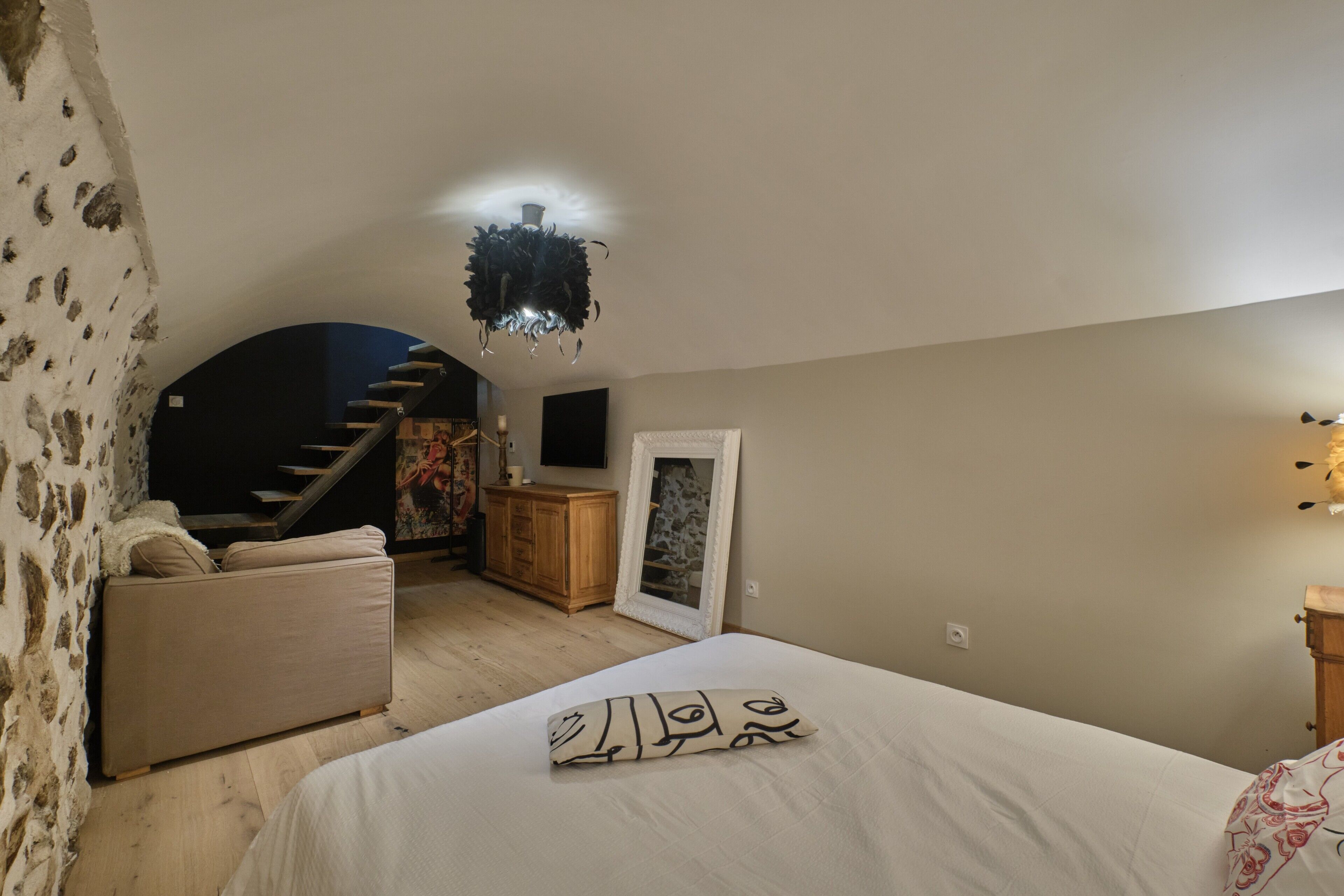 Ein Schlafzimmer mit Bett, Sofa, Treppe und Spiegel.