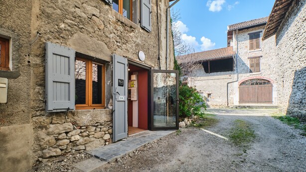 Un edificio in pietra con vialetto ghiaioso, una porta in legno e un piccolo giardino.