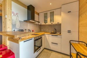 A modern kitchen with wooden countertops, white cabinets, a built-in oven, and a small dining area with a wooden table and chairs.