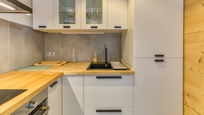 A modern kitchen with white cabinets, a wooden countertop, a sink, and a built-in oven. - Apartment 'Alpe D'huez' with Mountain View and Balcony (Huez)