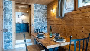 A wooden dining table with stone walls, a bottle, and bowls. - Apartment 'La Bergerie' with Mountain View, Private Terrace and Wi-Fi (La Giettaz)