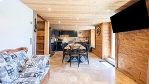 Une cuisine moderne avec des meubles en bois, un coin repas comprenant une table et des chaises, et un canapé agrémenté de coussins à motifs.