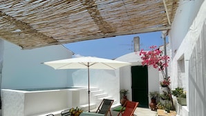 Zona relax all'aperto, riparata, con tavolo, sedie e divano.