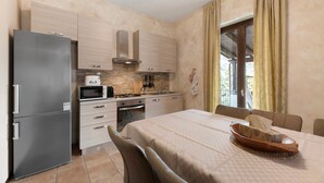 A compact kitchen with a refrigerator, microwave, stove, and sink. There is a dining table with chairs and a window with curtains. - Apartment 'Liivv House  - Lake Como' with Lake View, Private Terrace and Wi-Fi (Gravedona ed uniti)