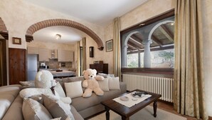 A living room with a sofa, a large teddy bear, a coffee table, and a view through a window. - Apartment 'Liivv House  - Lake Como' with Lake View, Private Terrace and Wi-Fi (Gravedona ed uniti)