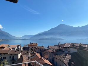 Una cittadina con edifici a tetti in terracotta, un lago e montagne sullo sfondo.