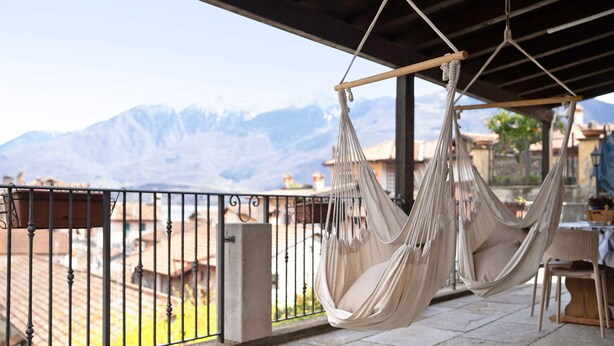 A balcony with two hammocks, a table, and chairs. - Apartment 'Liivv House  - Lake Como' with Lake View, Private Terrace and Wi-Fi (Gravedona ed uniti)