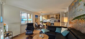 A modern living room with a black leather sofa, a coffee table, and a dining area with a table and chairs.