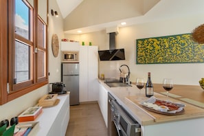 Una cocina moderna con horno integrado, microondas y lavaplatos. Hay dos copas de vino y botellas sobre la encimera.