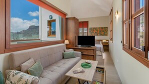 A living room with a sofa, a coffee table, a TV, and a view of the outdoors.