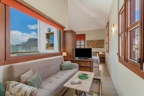 Una sala de estar con un sofá, una mesa de centro, un televisor y vistas al exterior.