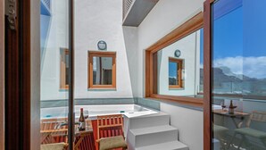 A balcony with a wooden table, chairs, and a bottle of wine.