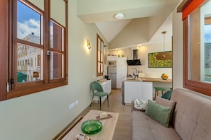 Un espacio habitable compacto con kitchenette, un sofá, una mesa de comedor y vistas amplias por ventanas grandes.