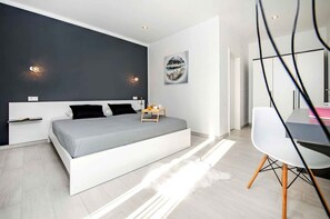 Een moderne slaapkamer met een groot bed, nachtkastjes, een bureau en een stoel.