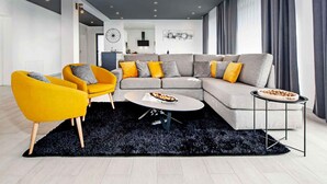 Un salon moderne comprenant un canapé d’angle, deux fauteuils, une table basse et une table d’appoint.