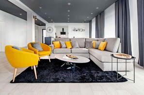 Een moderne woonkamer met een hoekbank, twee fauteuils, een salontafel en een bijzettafeltje.