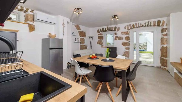 A modern kitchen with a wooden table, black chairs, and a built-in stove. - Holiday home with swimming pool and barbecue (Grižane)