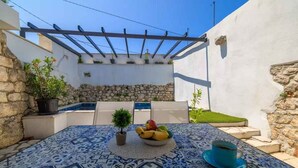 A patio with a tiled table, a bowl of fruit, a potted plant, and a blue cup. - Holiday home with swimming pool and barbecue (Grižane)