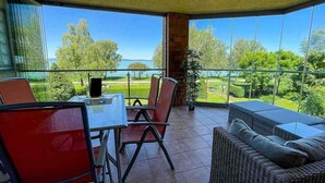 Ein geräumiger Balkon mit Tisch und Stühlen, der Blick auf einen Golfplatz und viel Grün bietet.