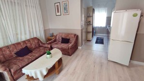 A living room with a sofa, a coffee table, a refrigerator, and a door leading to a kitchen. - Holiday apartment near the beach with a large terrace (Siófok)