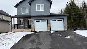 Ein zweistöckiges Haus mit Garage, Stein Fundament und Auffahrt.