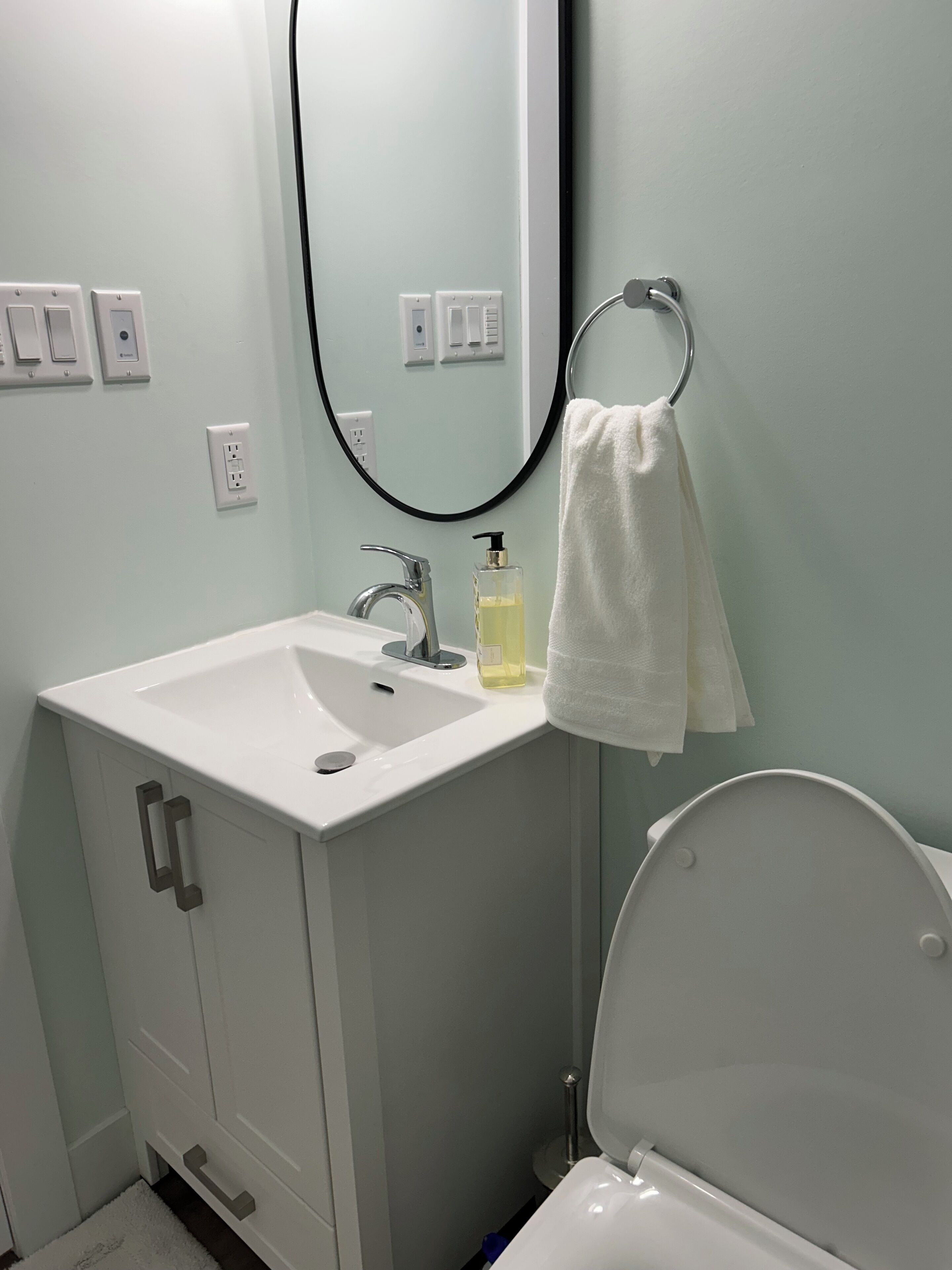 A bathroom with a white sink, a mirror, a towel rack, and a toilet.