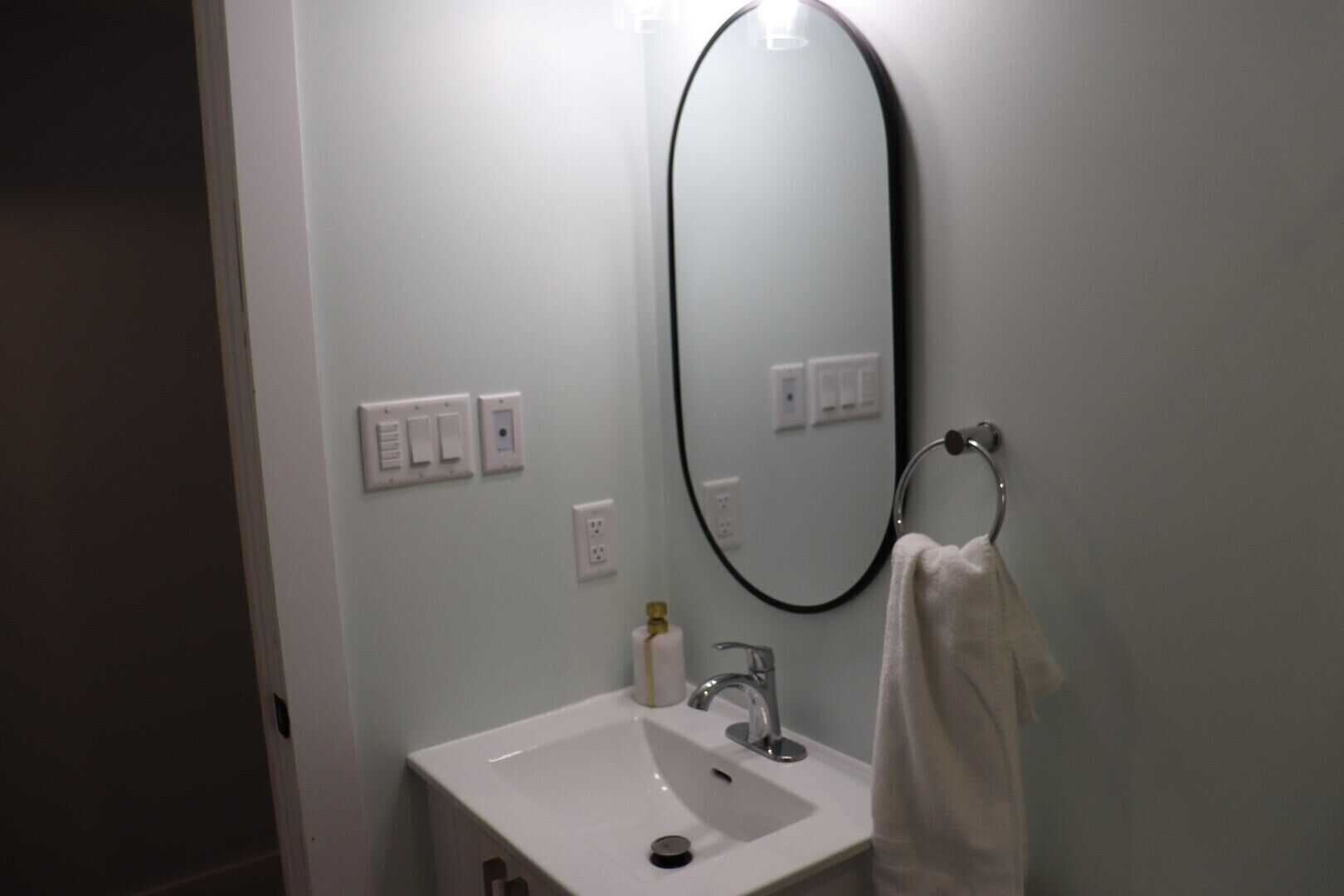 A bathroom with a white sink, a mirror, and a towel rack.
