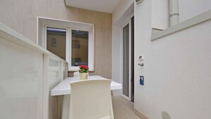 A narrow hallway with a white door, a window, and a small table with a chair. - Holiday apartment with air conditioning, internet, balcony and pool (Lignano)