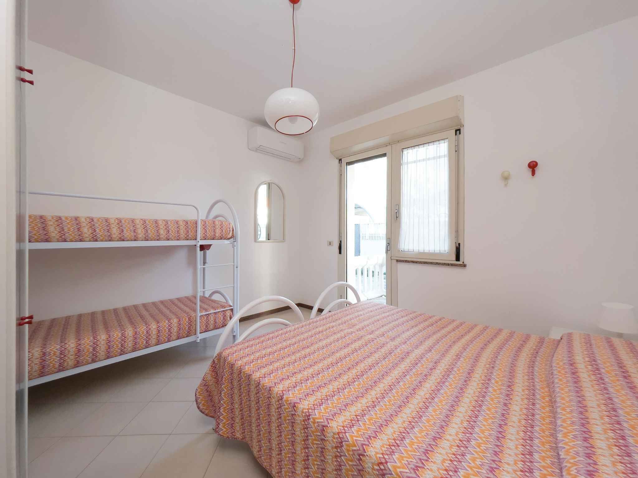 Un dormitorio con literas, una cama individual, una silla, un ventanal y un equipo de aire acondicionado.