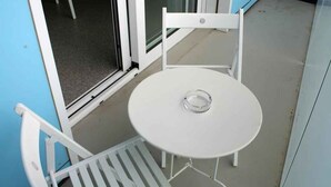 A small outdoor seating area with a white table and two white chairs.