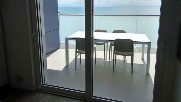 En balkon med et bord og stole, der ud til et vandområde.