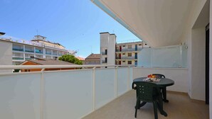 Un balcone con tavolo e sedie, vista su una zona residenziale con diversi edifici.