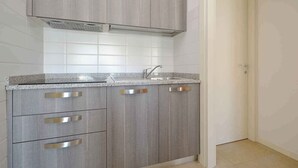 Una cucina con mobili grigi, un lavello in acciaio inossidabile e uno schienale piastrellato.