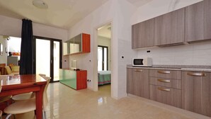 A modern kitchen with wooden cabinets, a microwave, and a dining area with a table and chairs.
