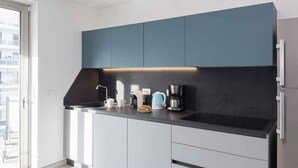 Una cucina moderna con mobili blu scuro, un piano di lavoro nero e un forno integrato.