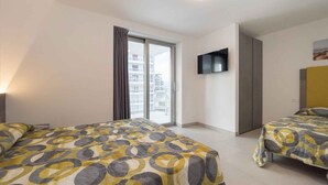 Camera d'albergo con due letti, televisione e balcone con vista sulla città.