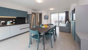 Una cucina moderna con zona pranzo, frigorifero e televisione a schermo piatto.