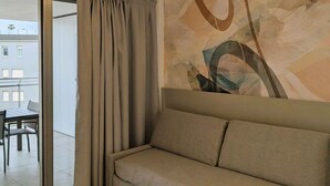 A modern living room with a sofa, a ceiling light fixture, and a large abstract painting on the wall.