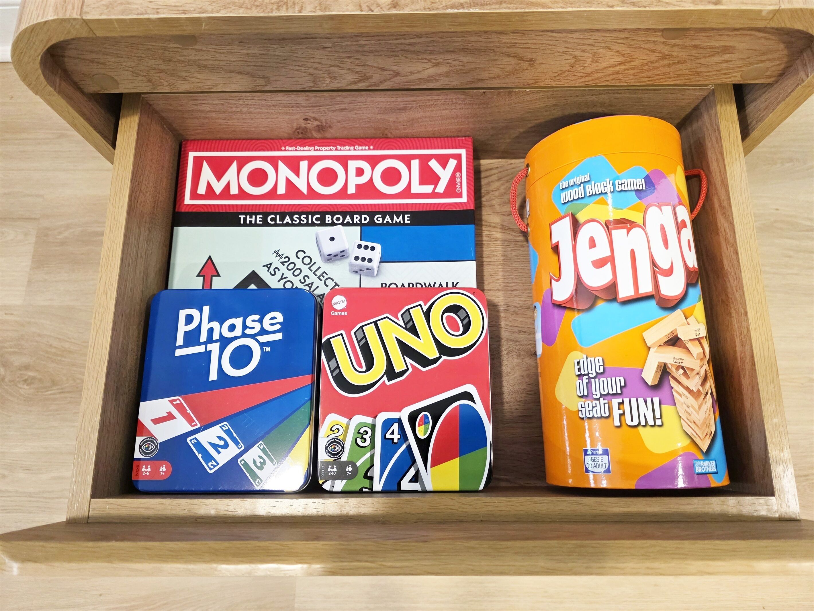 Laatikossa on lautapelit Monopoly, Phase 10 ja Jenga.