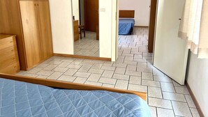 Une chambre à coucher avec un lit, une armoire en bois et un miroir qui reflète une autre pièce.