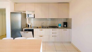 A compact kitchen with a refrigerator, microwave, sink, and stove. - Holiday flat with balcony and air conditioning (Lignano)