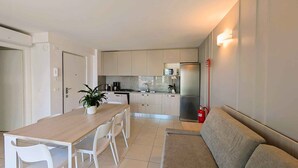 A modern kitchen with a dining table, chairs, a sofa, and a microwave. - Holiday flat with balcony and air conditioning (Lignano)