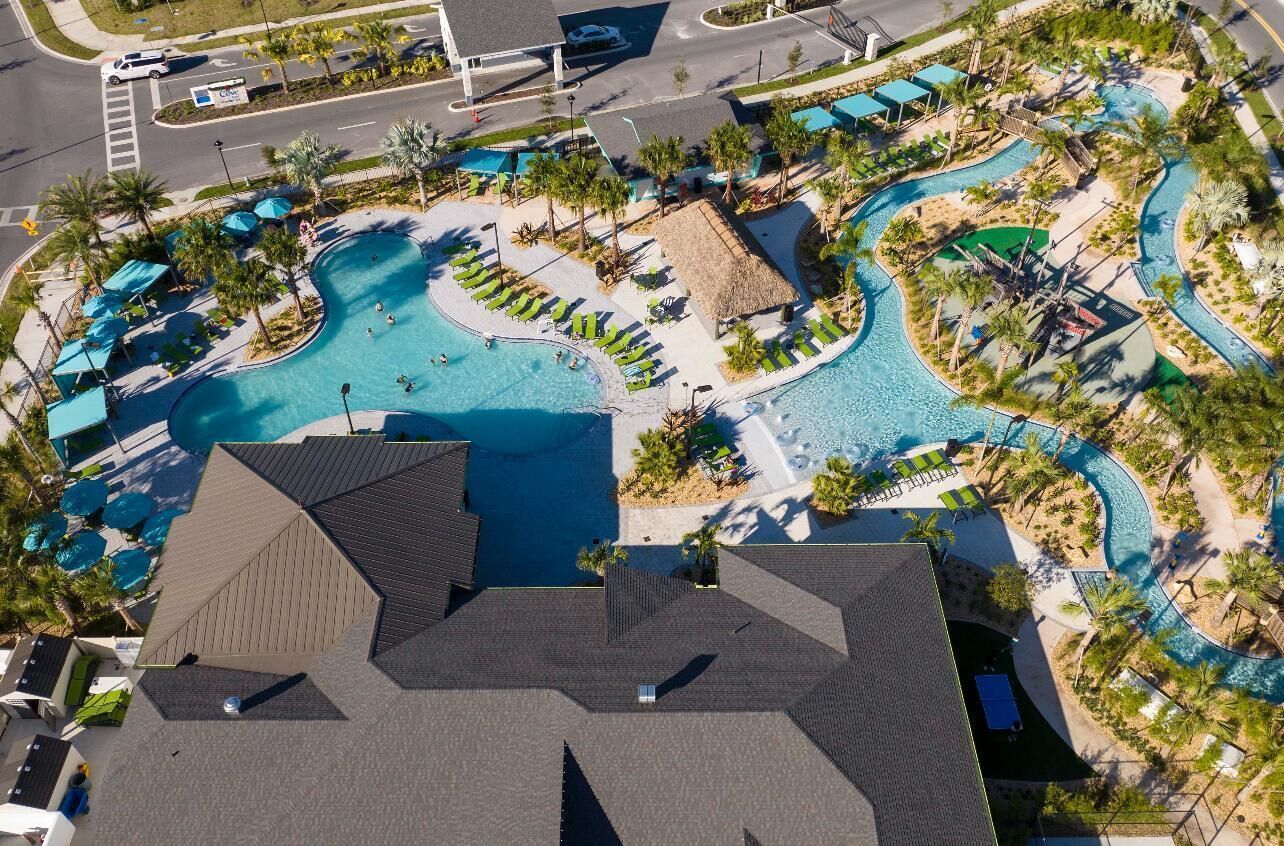 An aerial view of a resort with a large central pool, multiple smaller pools, and a variety of sun loungers and umbrellas.
