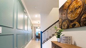 A hallway with teal walls, a wooden console table, and a staircase with a blue railing. - Storey Lake Resort, Private Pool, Near Famous Attractions!! (Kissimmee)
