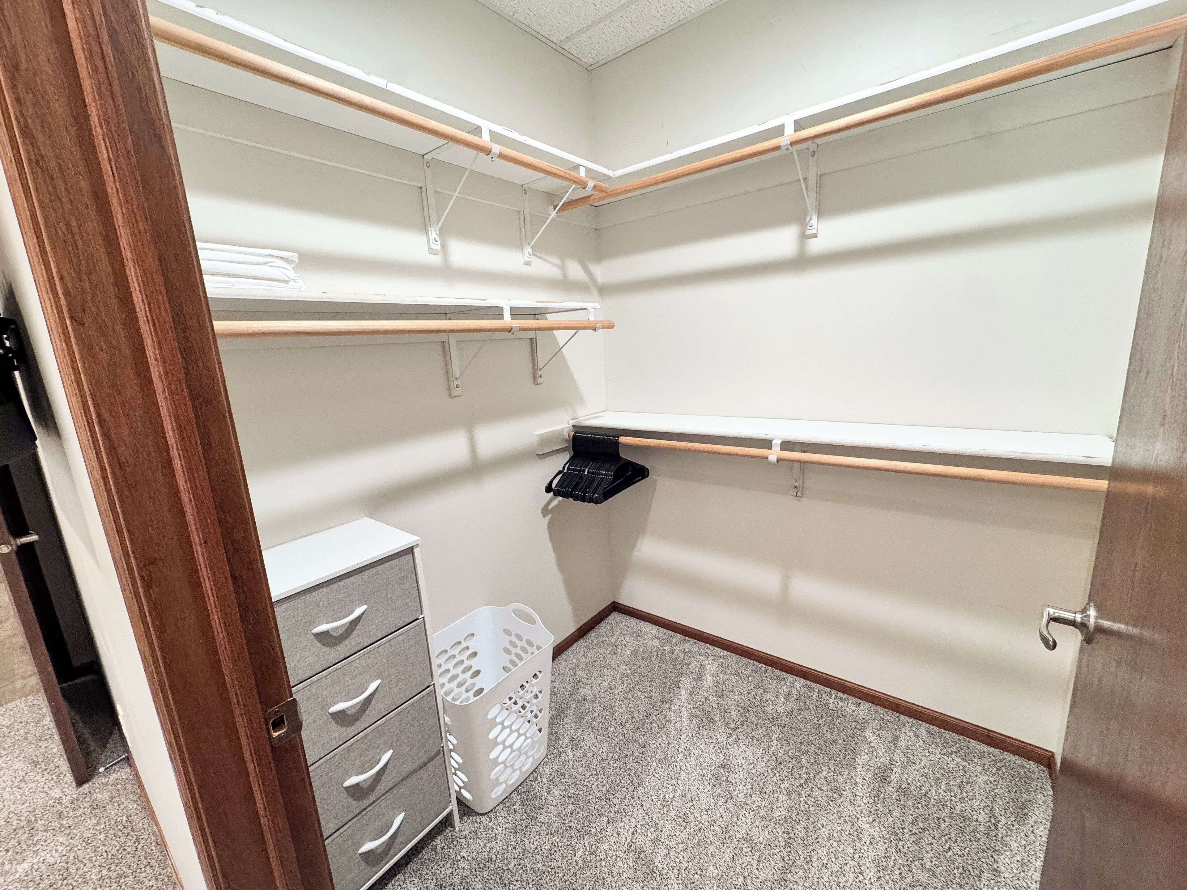 Un vestidor con repisas abiertas, una puerta de madera y un cesto de ropa.