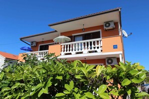 Ein zweistöckiges Gebäude mit Balkon, Klimaanlagen und einer Satellitenschüssel.