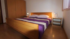 A bedroom with a wooden bed, a nightstand with a lamp, and a wardrobe.